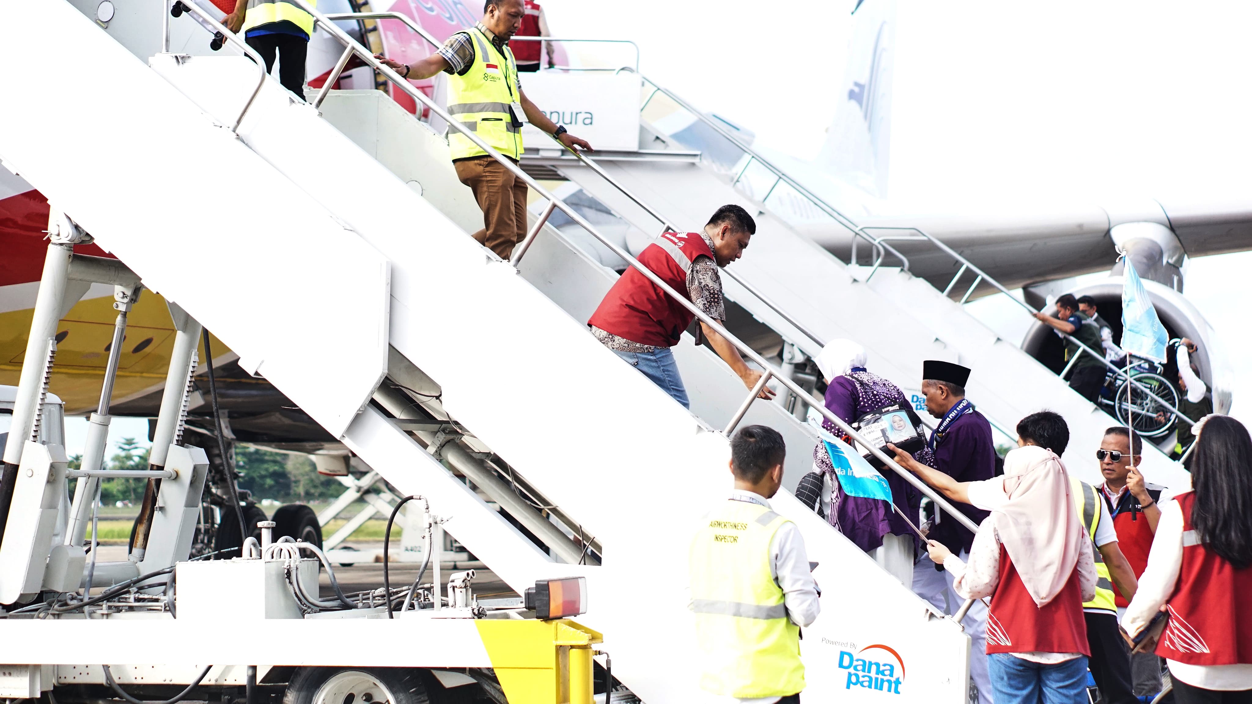 RAMAH LANSIA: Petugas haji membopong jemaah lansia masuk ke pesawat, di Bandara Syamsudin Noor, Banjarbaru, Minggu (12/5/2024).(Foto: Sheilla Farazela/Radar Banjarmasin)