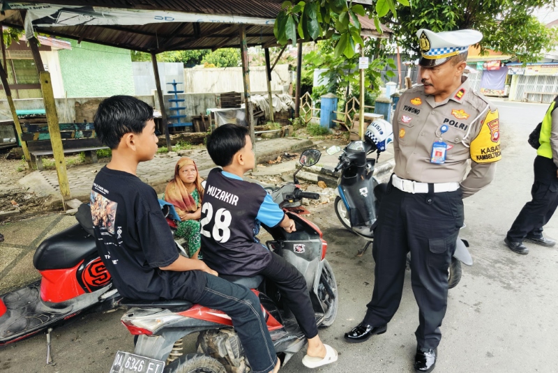WEJANGAN: Kasat Lantas Polres HSU Iptu Yuwono, saat memberikan penyadaran persuasif pada dua anak yang berkendara tidak memakai helm di Jalan Empu Jatmika Kabupaten HSU.