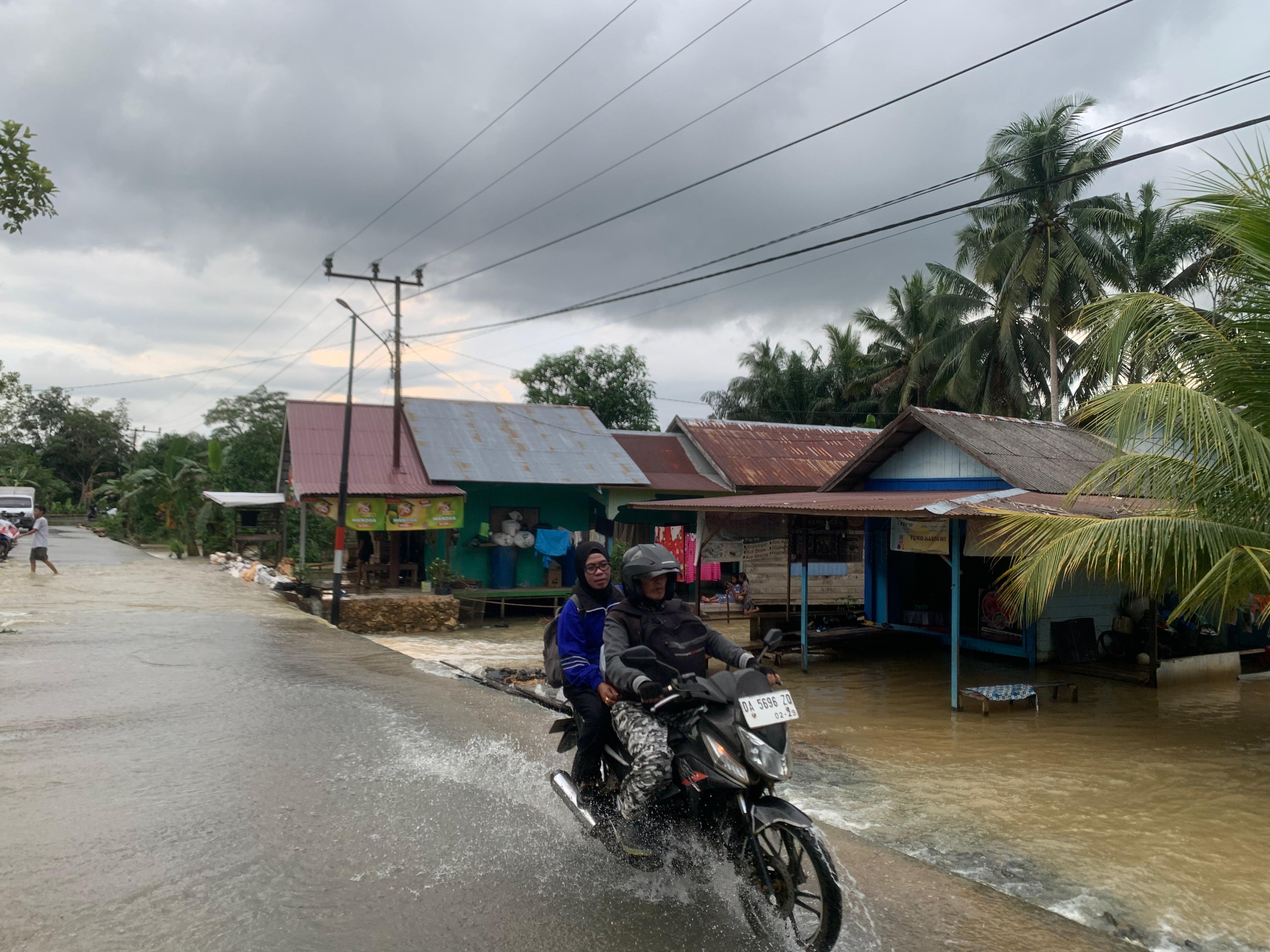 MASIH TINGGI: Banjir masih menggenangi Kusan Hulu, Tanah Bumbu, akibat meluapnya air DAS Kusan. Pengendara motor terpaksa melewati genangan air untuk beraktivitas. (Foto:Zulqarnain/Radar Banjarmasin)