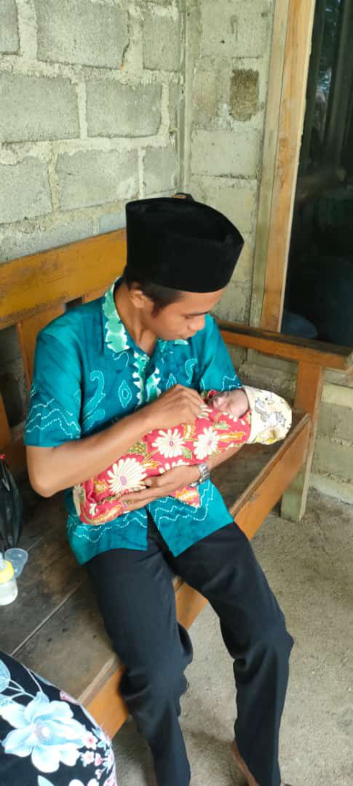 DIRAWAT:Kepala Desa Masingai II, Tatak Adi Rahmanto menggendong bayi yang ditemukan di semak kabun karet, Sabtu (15/6/2024).(Foto:Kades Masingai II untuk Radar Banjarmasin)