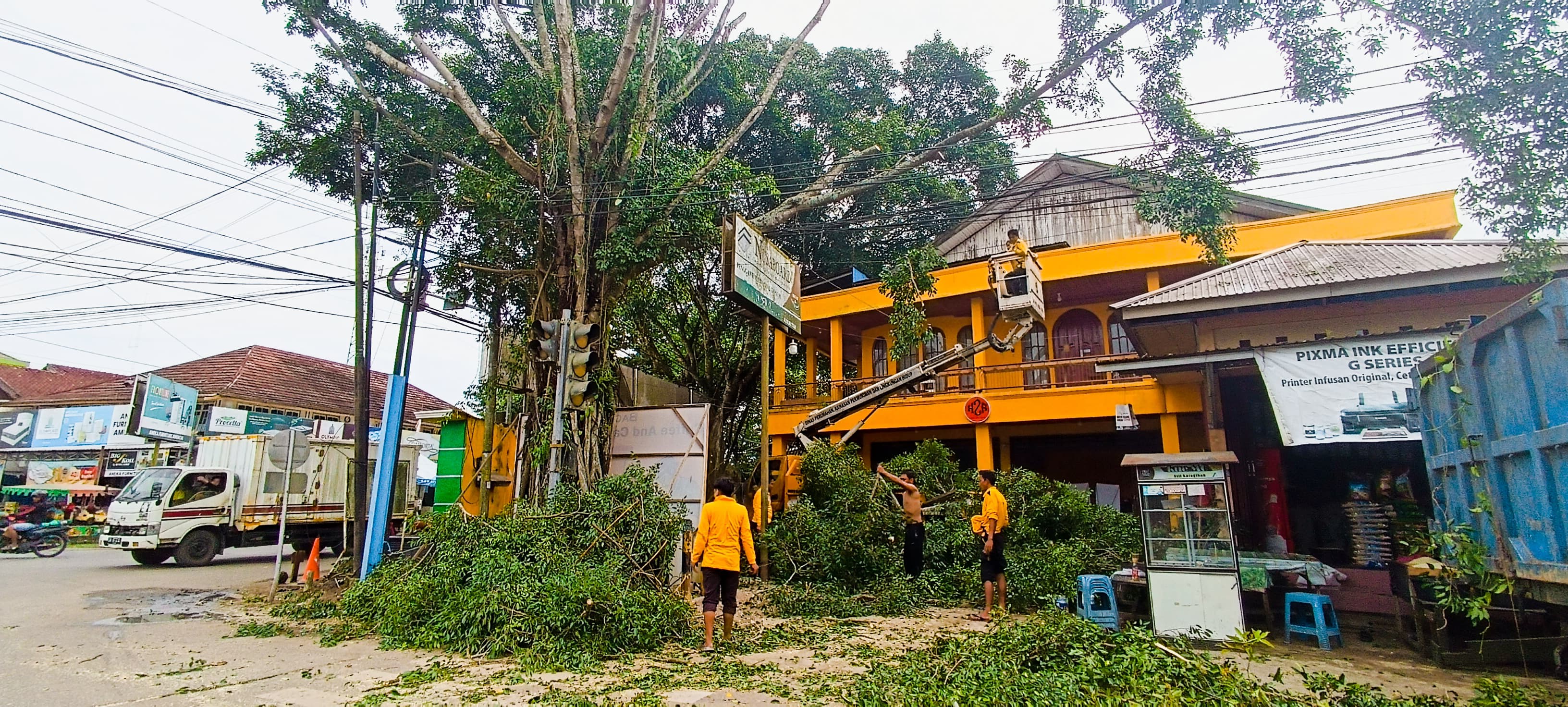 ANTISIPASI: Dinas Perkim-LH HSU memangkas sejumlah pohon rimbun yang ada di tepi jalan Kota Amuntai menggunakan truk crane mini. (Foto: M.Akbar/Radar Banjarmasin)