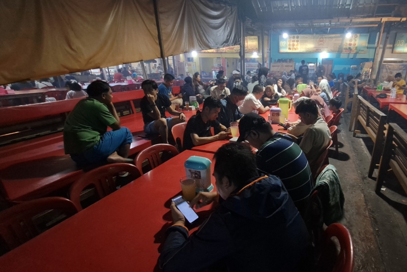SABAR MENANTI: Pengunjung Pasar Ikan Modern (PIM) menanti pesanannya selesai dibakar.