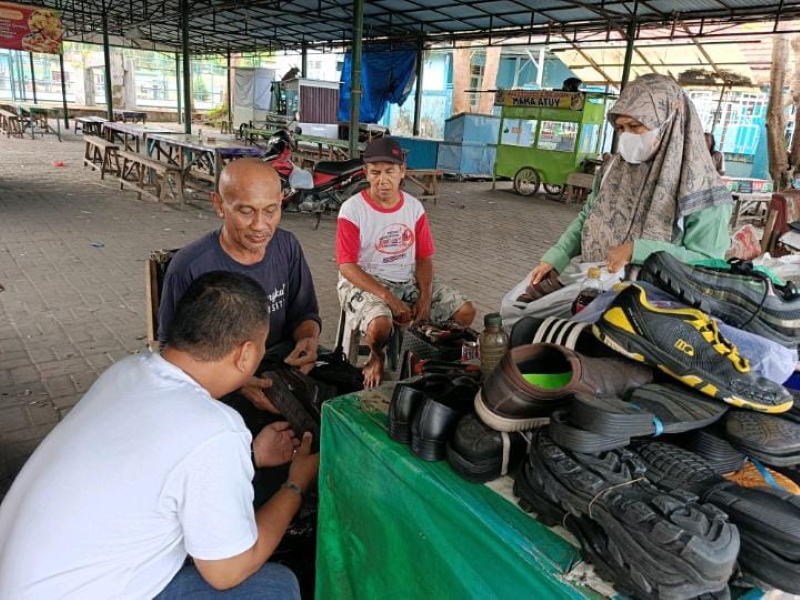 MENJAHIT: Rahmadi sedang sibuk menjahit sepatu yang rusak di lapaknya, Jumat (19/7).