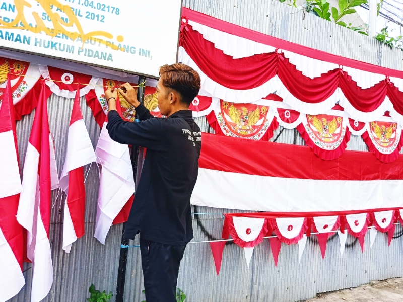 BENDERA: Ego Hendra saat memajang bendera yang ia jual di Jalan Panglima Batur, Jumat (26/7).