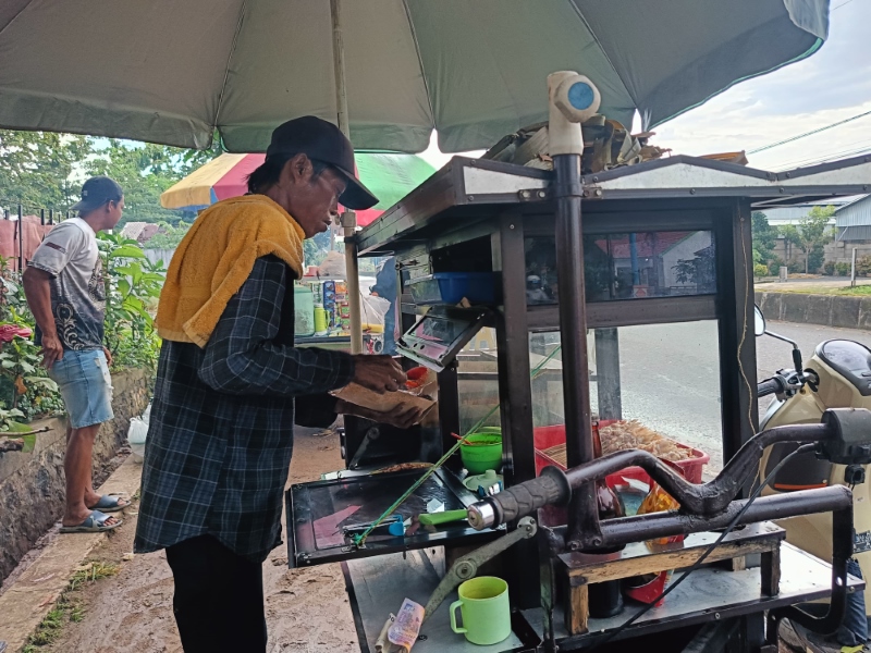 MENGEMAS: Junaidi saat menyiapkan sate untuk pelanggannya, Selasa (30/7).