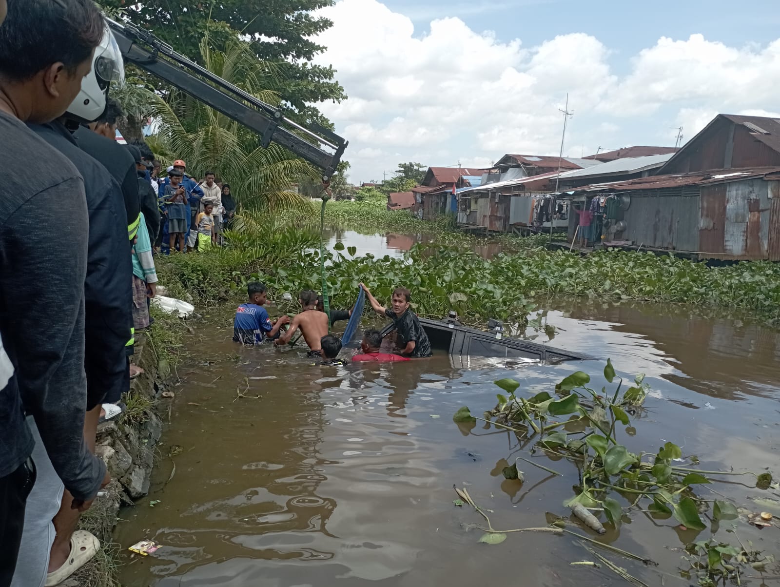 INSIDEN:Mobil BPK Komdar tercebur ke Sungai Japri Zam Zam setelah menghindari kecelakaan dengan kendaraan lain, Senin (5/8/2024).(Foto:relawan untuk Radar Banjarmasin)