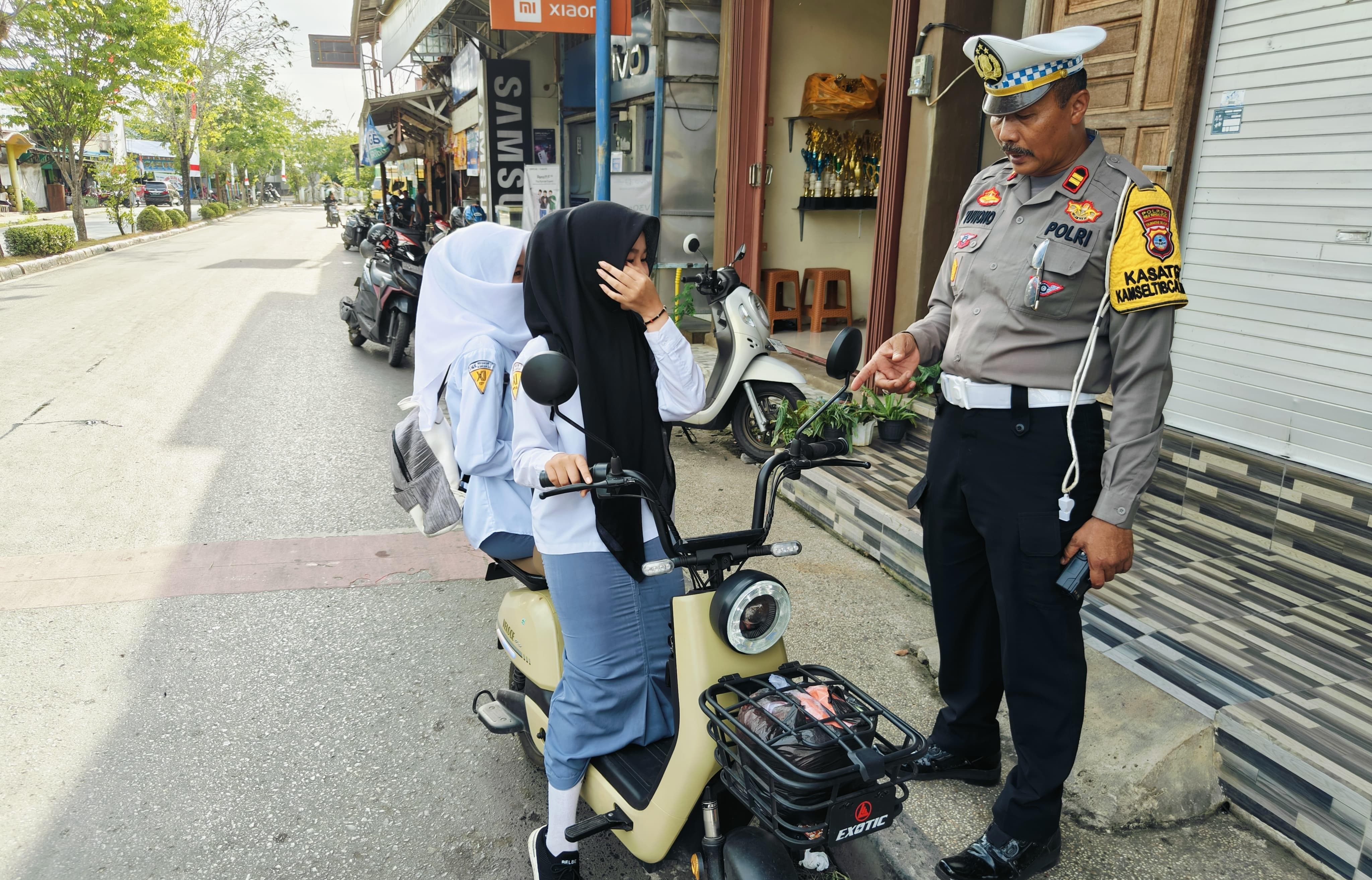 TERHENTI: Kasat Lantas Polres HSU, Iptu Yuwono saat mengatur lalu lintas di Simpang Empat Paliwara Kota Amuntai, dapati pengguna sepeda listrik tak pakai helm. (Foto: M.Akbar/Radar Banjarmasin)