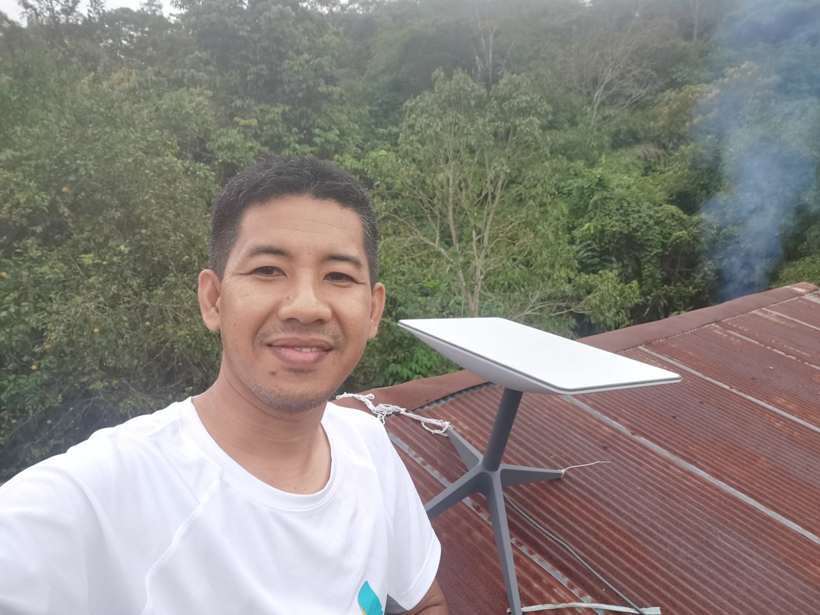 STARLINK: Jamaluddin Rahmat naik ke atas atap sekolah untuk menunjukkan alat Starlink yang telah dipasang dan siap digunakan. (Foto: Jamaluddin Rahmat untuk Radar Banjarmasin)