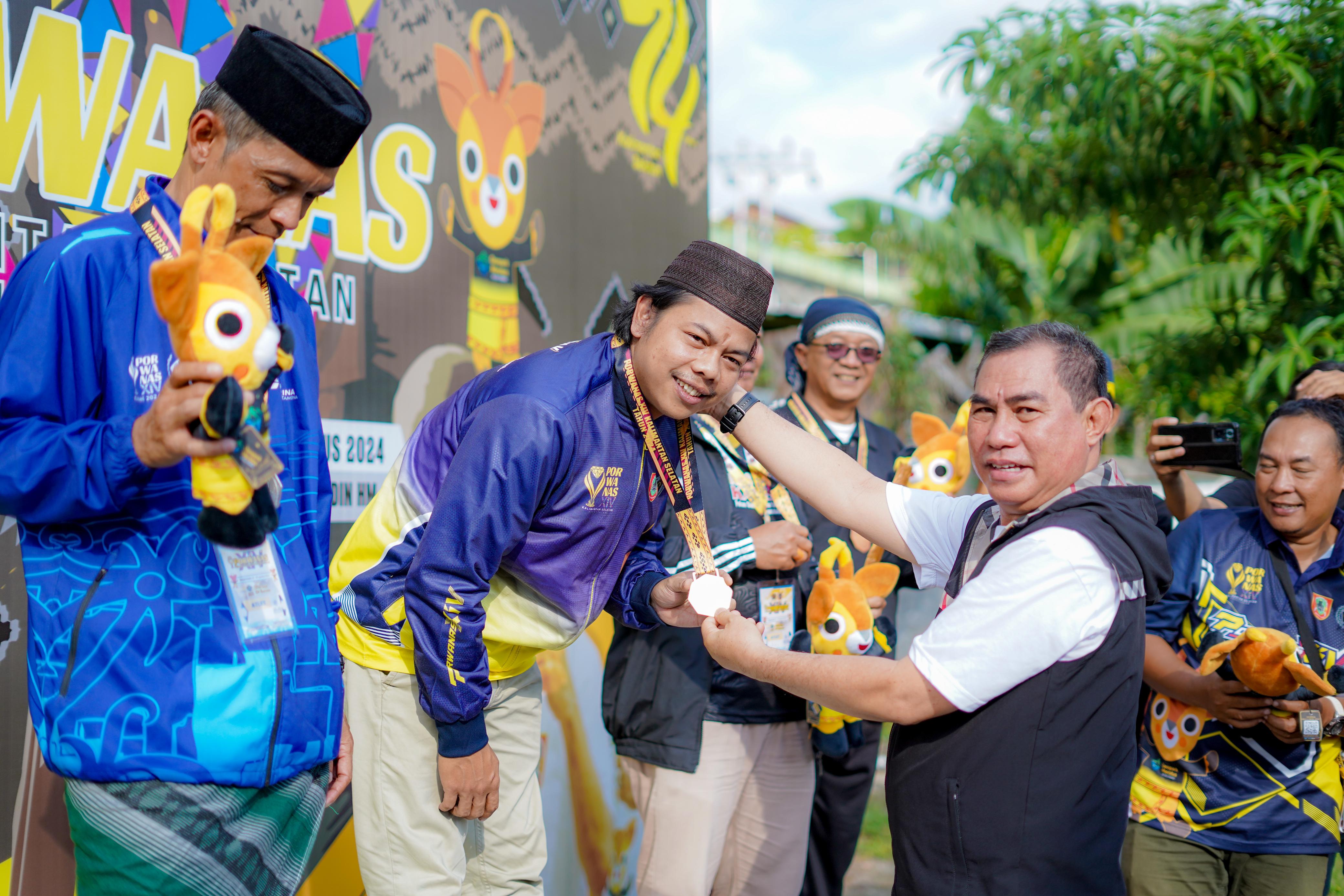 JUARA:Fahrul Raji, saat menerima medali emas yang dikalungkan Ketua PWI Kalsel Kalsel, Zainal Helmie di GOR Hasanuddin HM Banjarmasin, Jumat (23/8/2024).(Foto:Ambol untuk Radar Banjarmasin)