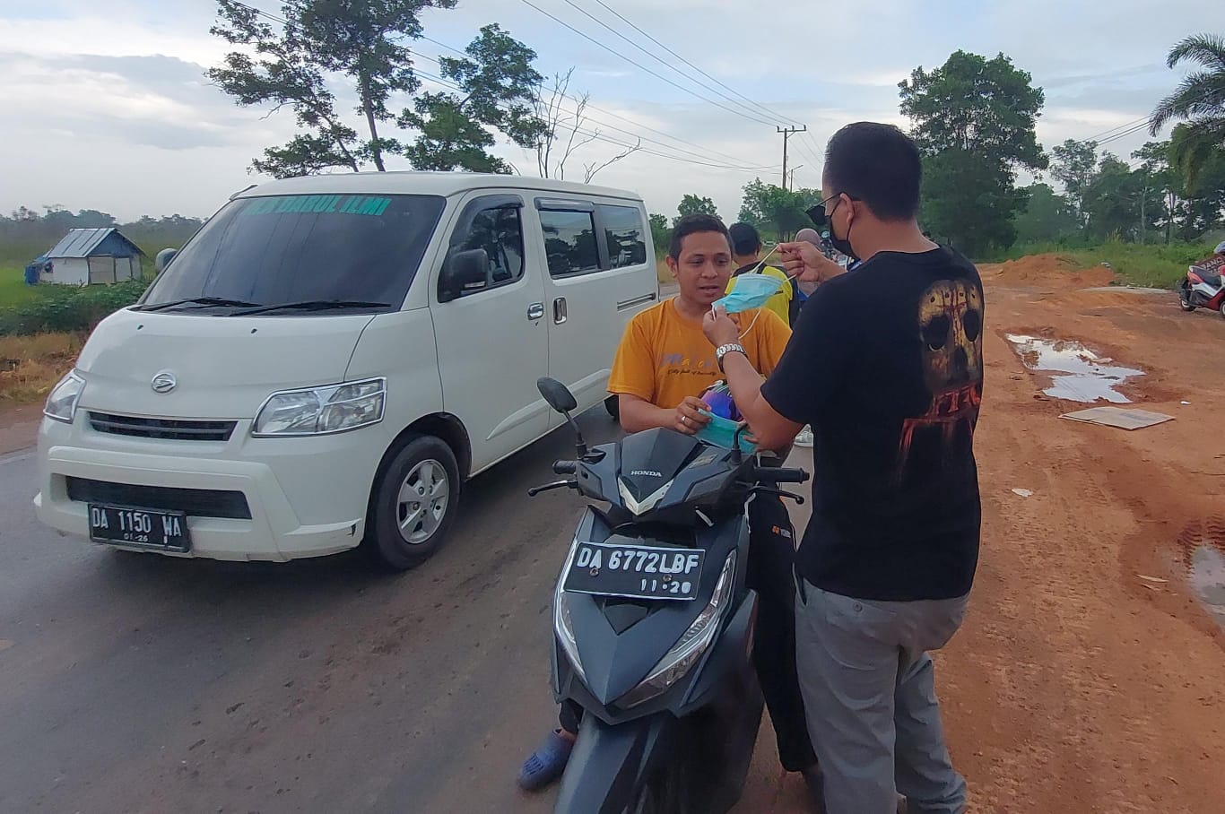 KABUT ASAP:Ketua DPD MPAI My Darling Kalsel, Muhammad Khaidir memasangkan masker ke pengendara motor di Jalan Nasional Desa Gunung Raja, Kecamatan Tambang Ulang, Minggu (29/9/2024).(Norsalim Yahya)