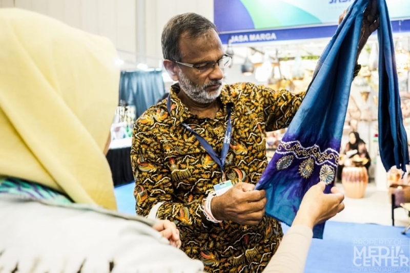 TERTARIK: Salah satu pengunjung Trade Expo Indonesia tengah mengamati kain sasirangan.