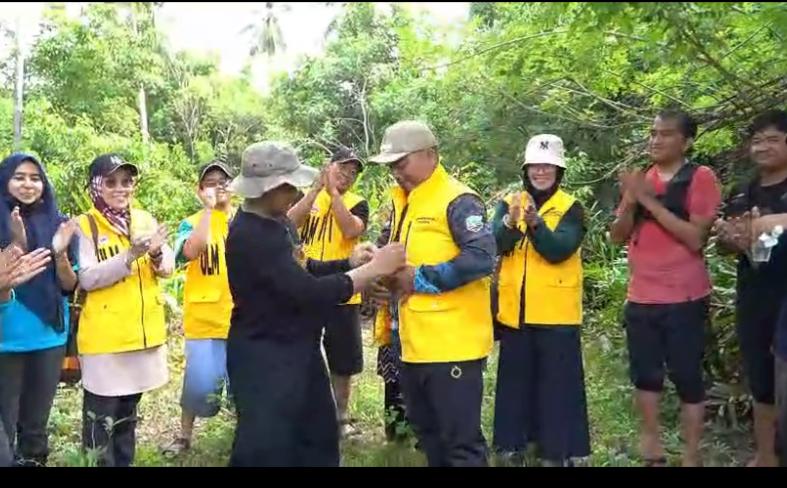 SIMBOLIS: Rusmin menyerahkan Rompi Kuning ULM kepada Kades Teluk Tamiang.