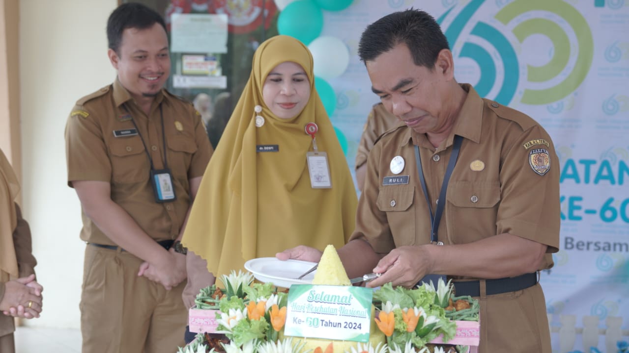 MOMEN HKN:Staf Ahli Bupati HST, Syahruli memotong tumpeng disaksikan Kadinkes HST, dr Desfi Delfiana Fahmi.(Foto: Kominfo HST)