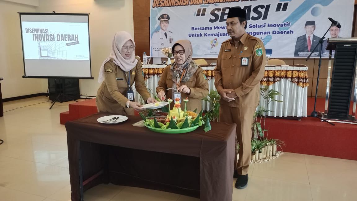 SIMBOLIS:Asisten Administrasi Umum, Narni memotong tumpeng sebagai simbol peluncuran aplikasi SERASI yang kini hadir dengan fitur baru, Senin (25/11/2024).(MC TANAH BUMBU)