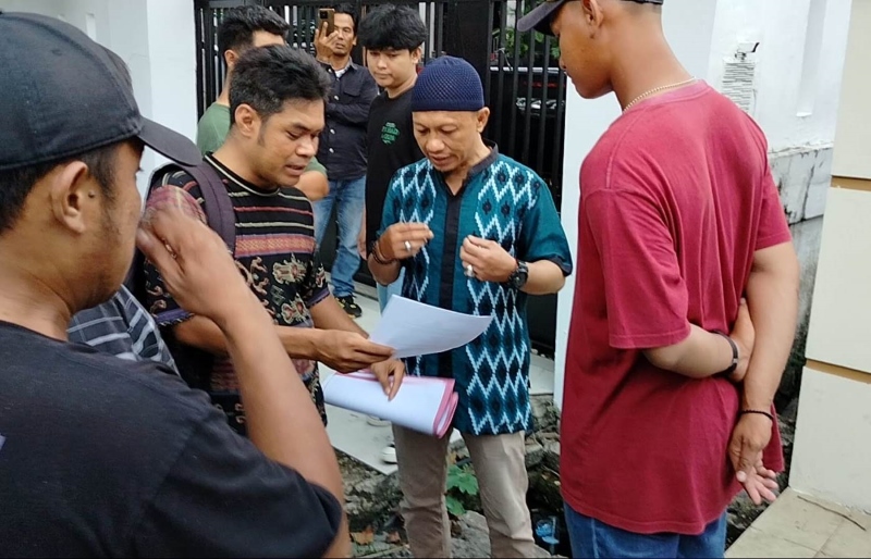 DIAMANKAN: Yose Riza (46) saat melihat surat perintah penangkapan dari anggota Polsek Banjarmasin Tengah berpakaian preman.
