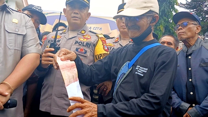 BUKA AMPLOP: Koordinator Aksi, Rachmadi memeriksa isi amplop yang terjatuh di tengah pendemo.