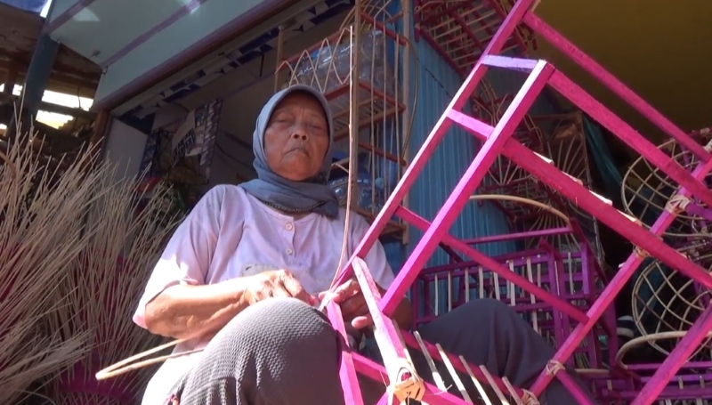 BEKERJA: Musini telaten mengikat rotan ke kerangka produk kerajinan keranjang.