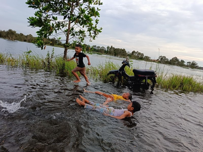 BERKAH: Warga yang datang memanfaatkan banjir untuk berenang, mencuci kendaraan, hingga memancing.
