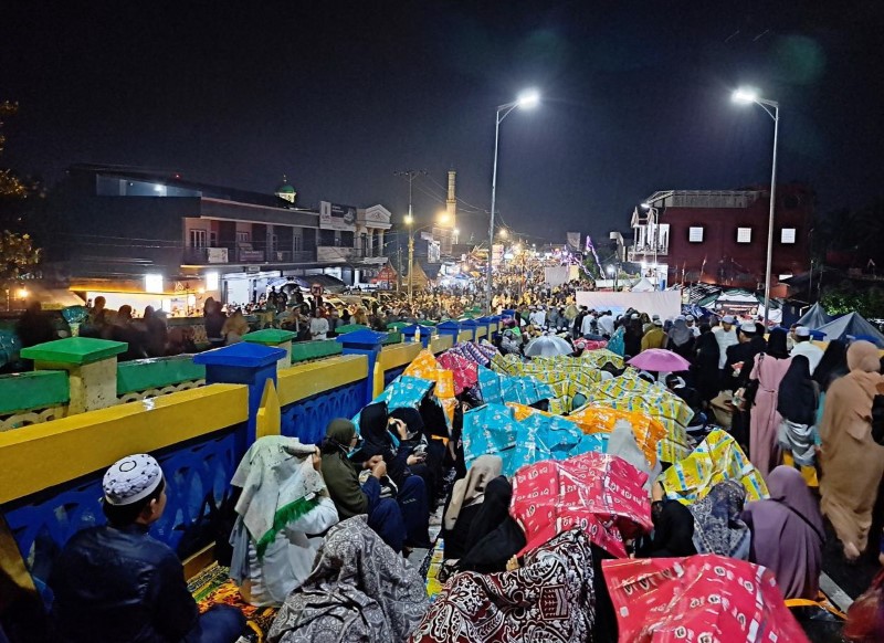 KEHUJANAN: Jemaah Haul Guru Zuhdi di atas Jembatan Sulawesi, Maret 2023. Diguyur hujan, jemaah menutupi diri dengan terpal dan jas hujan.