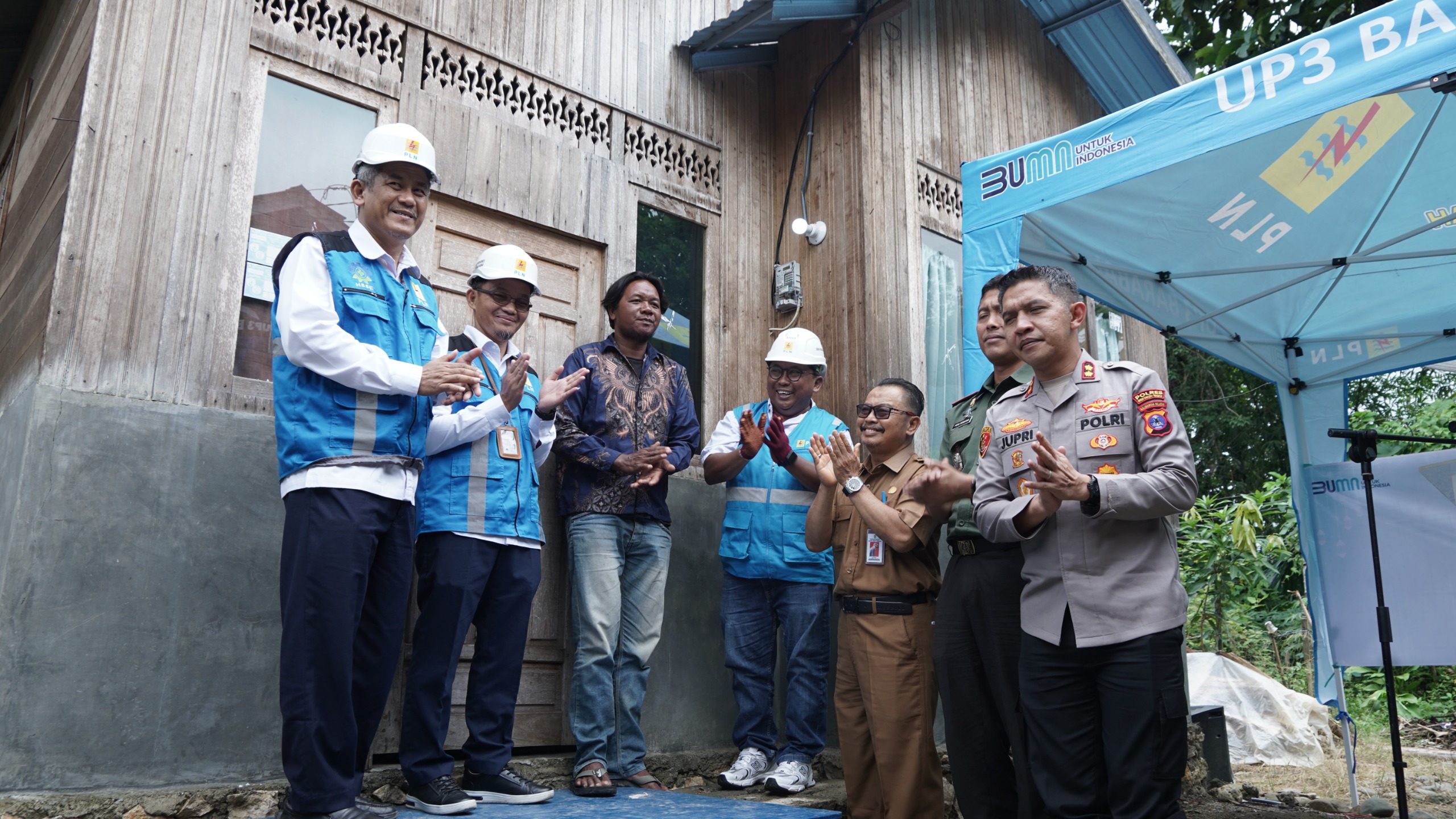 MOMEN BAHAGIA: Senior Manager Niaga dan Manajemen Pelanggan PLN UID Kalselteng, Agus Tri Suardi (tengah) menyalakan listrik program LUTD di rumah Muhammad Arsani, Desa Mandingin, Kabupaten HST.