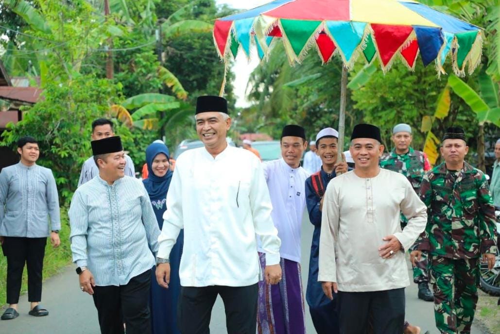 DISAMBUT: Rombongan Wabup HSU Hero Setiawan (tengah) Ketua DPRD HSU H Fadilah (kanan) dan Sekda HSU Adi Lesmana, disambut tradisi payung hadrah saat safari Ramadan oleh warga Desa Pihaung, di Kecamata