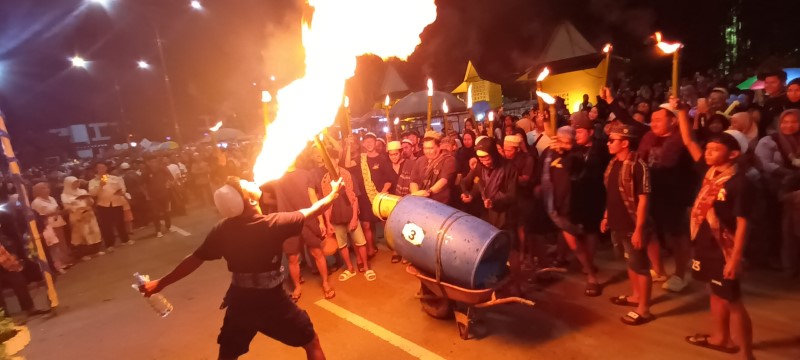 TALINTINGAN: Salah satu peserta pawai talintingan melakukan atraksi semburan api sembari diiringi musik dari alat sederhana.