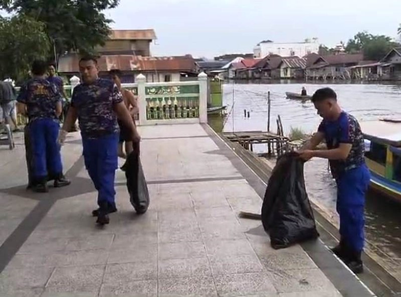 BERSIH-BERSIH: Personel Polairud Polresta Banjarmasin memunguti sampah di kawasan dermaga Makam Pangeran Sultan Suriansyah, Sungai Kuin, Kamis (27/3) pagi.