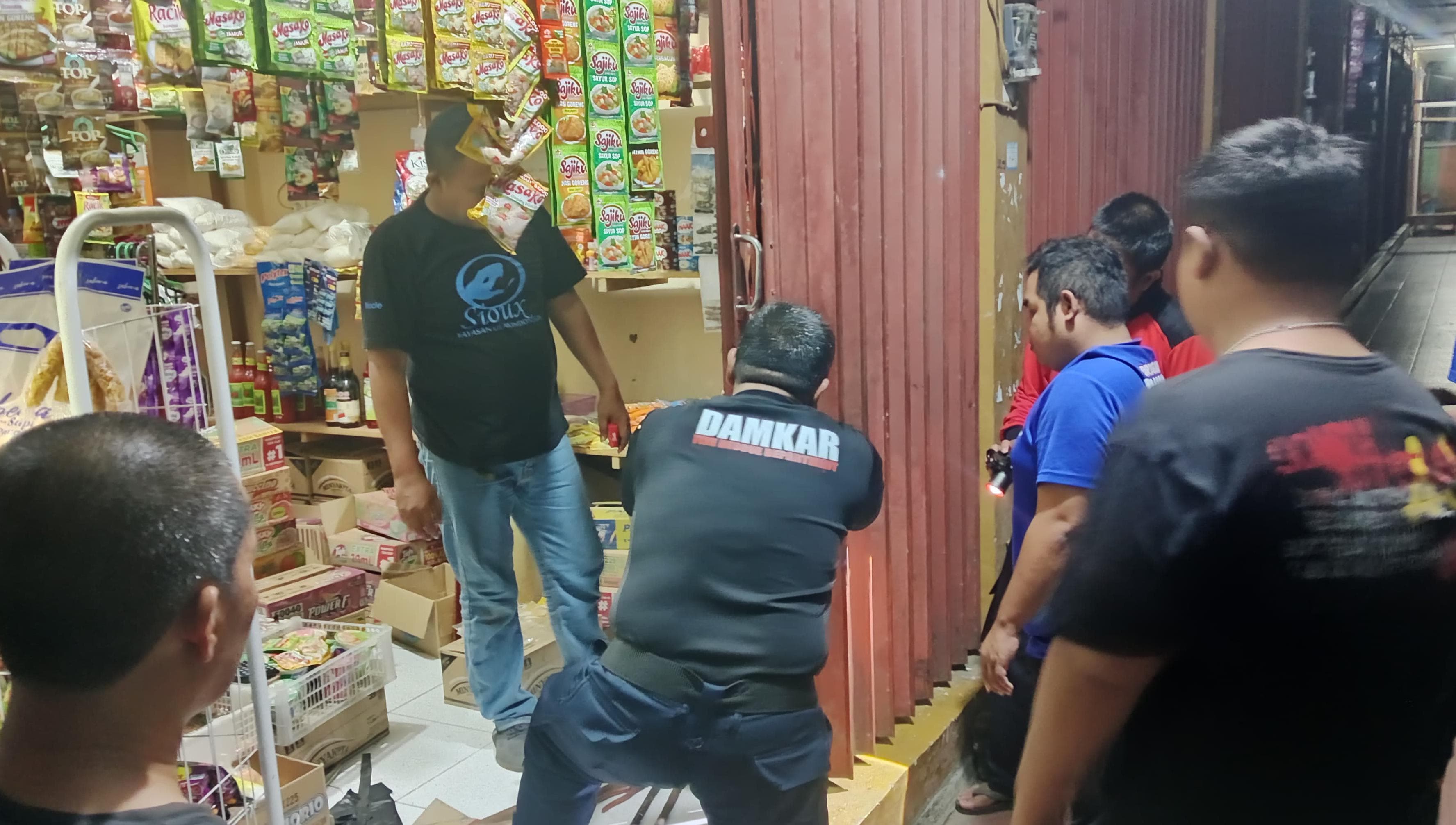 MEMBANTU:Tim Damkar HSU memperbaiki pintu toko warga di Kecamatan Sungai Pandan, Sabtu (5/4/2025) dini hari.(Foto:Damkar HSU untuk Radar Banjarmasin)