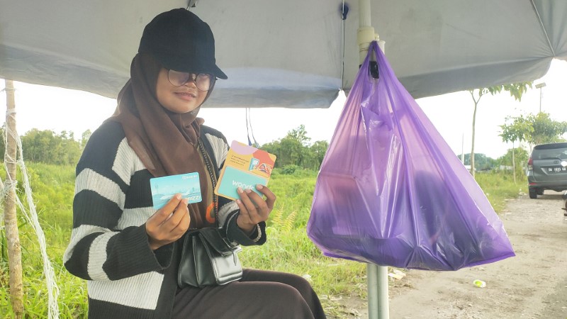 BERBAGAI KARTU: Anjani Aji Wijayanti menunjukkan sejumlah kartu e-Money dari berbagai bank yang dijualnya di tepi Jalan Bandara Syamsudin Noor, Selasa (8/4) sore.