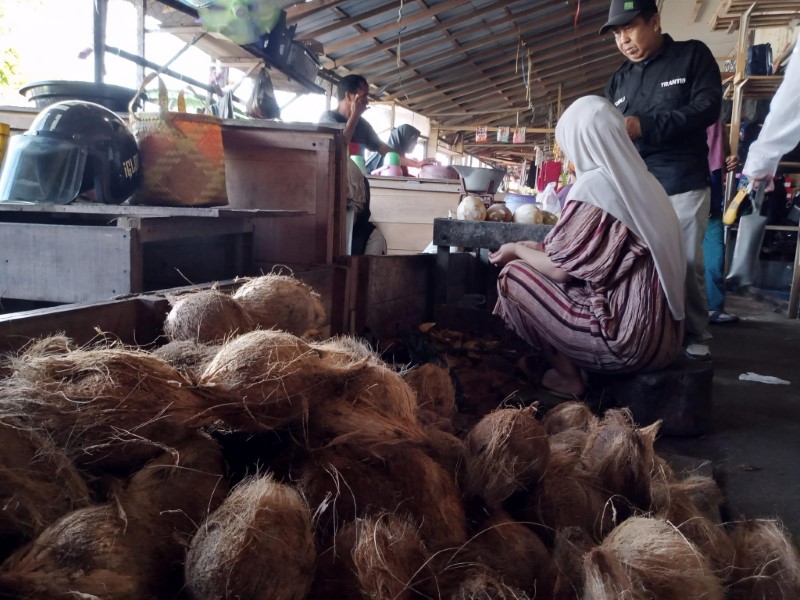 MENGUPAS: Pedagang kelapa parut di Pasar Astambul, Kabupaten Banjar mengeluhkan kenaikan harga bahan baku kelapa.