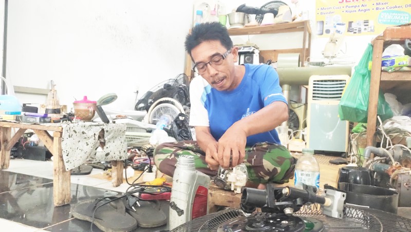 MEMPERBAIKI: Bahrani (55) tengah memperbaiki komponen kipas angin di kios sederhananya di Pasar Bauntung Banjarbaru, Jumat (5/4).