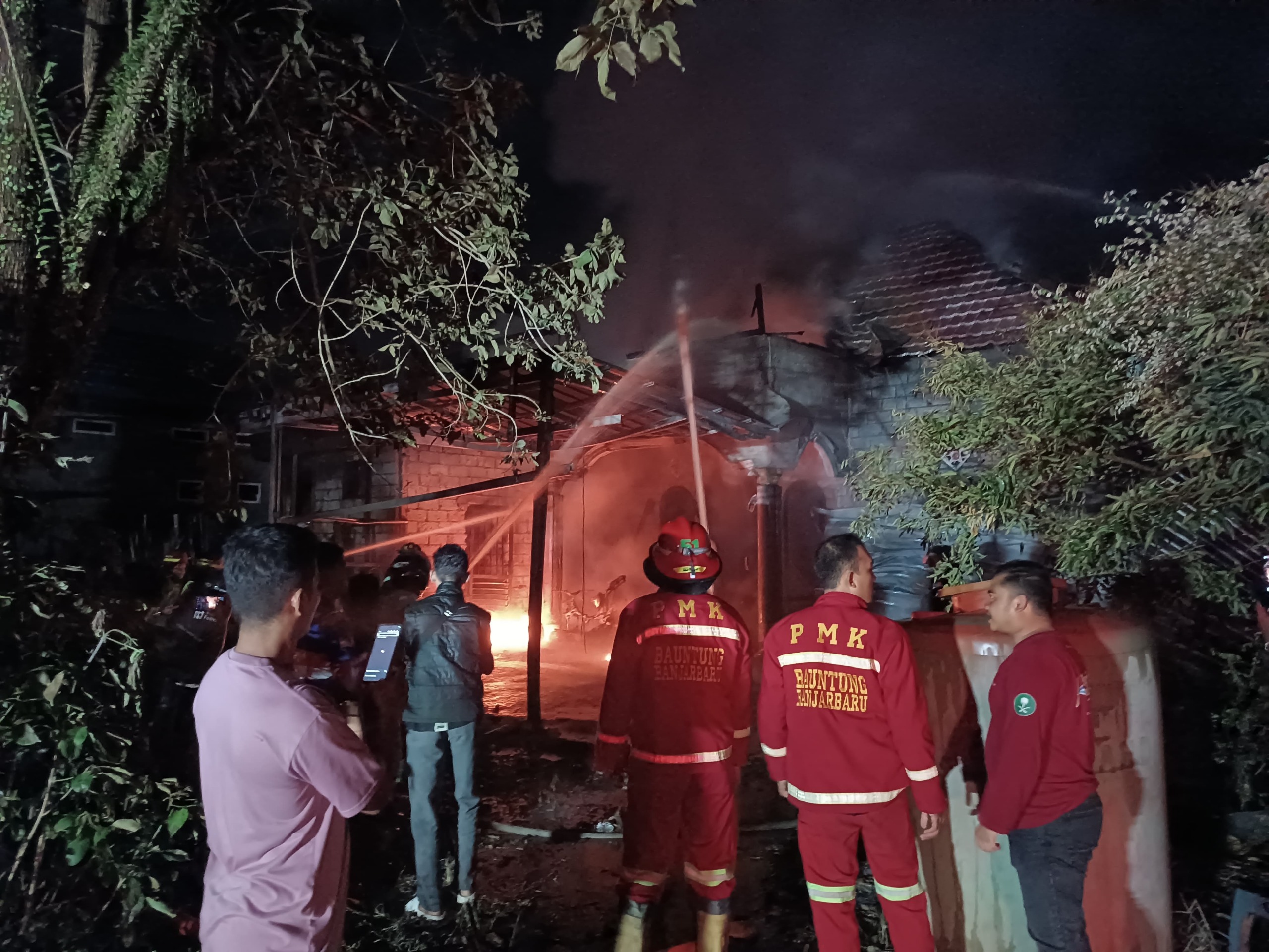 PEMADAMAN: Petugas pemadam dan relawan mengatasi sebuah rumah yang terbakar di Gang Kamelia Jalan Sidomulyo, Banjarbaru, Selasa (15/4) malam. (Foto: Humas Polsek Liang Anggang)