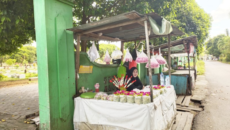 DI LUAR: Saniah (50) sedang berjualan bunga tabur di samping gapura Kuburan Muslimin Guntung Lua, Kemuning, Rabu (16/4) pagi.