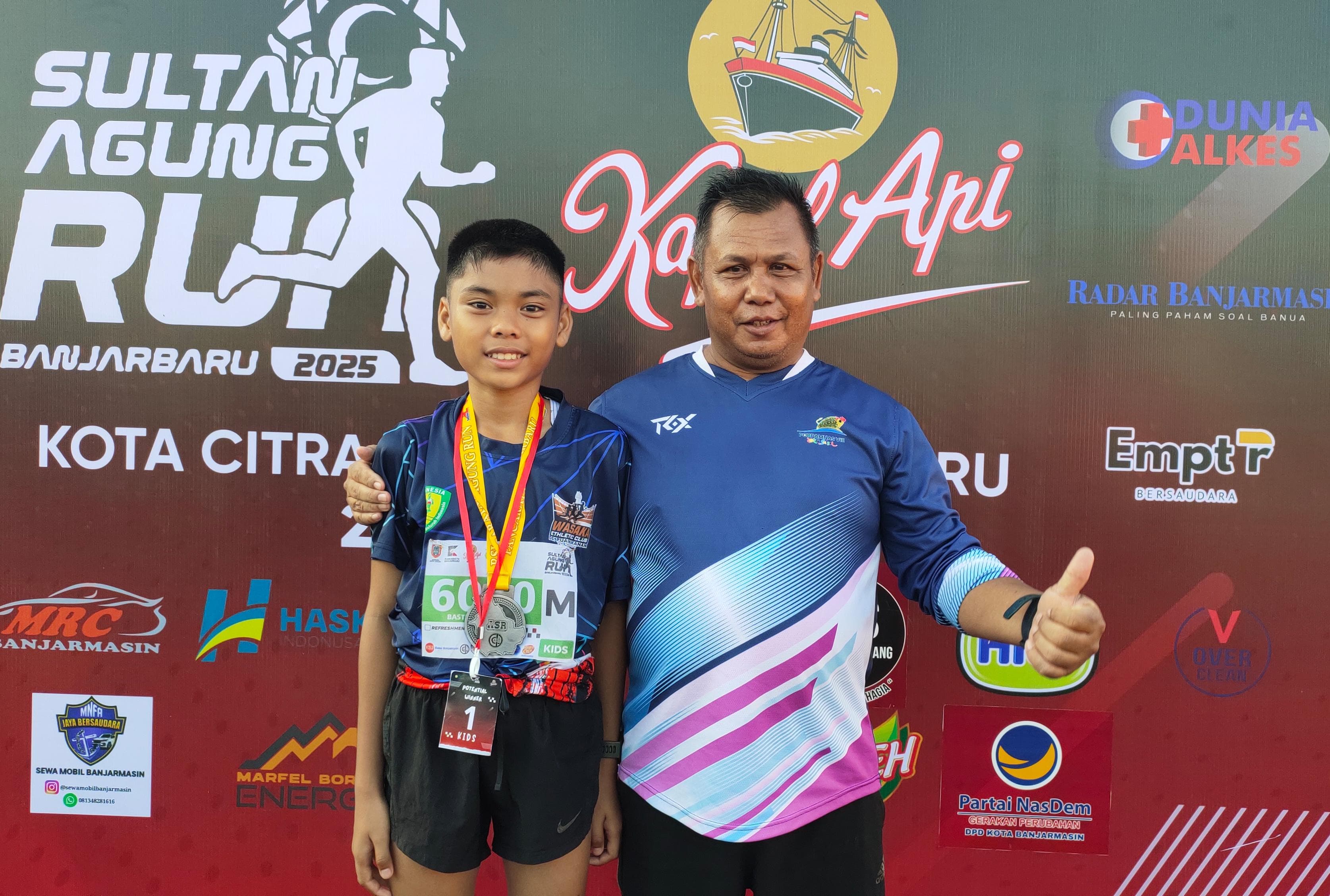 BANGGA: Bastian Al Avares bersama Coach M Suryadi dari Wasaka Athletic Club Tabalong berpose usai meraih juara pertama kategori Kids Run 3K di ajang Sultan Agung Run Banjarbaru 2025, Minggu (20/4)