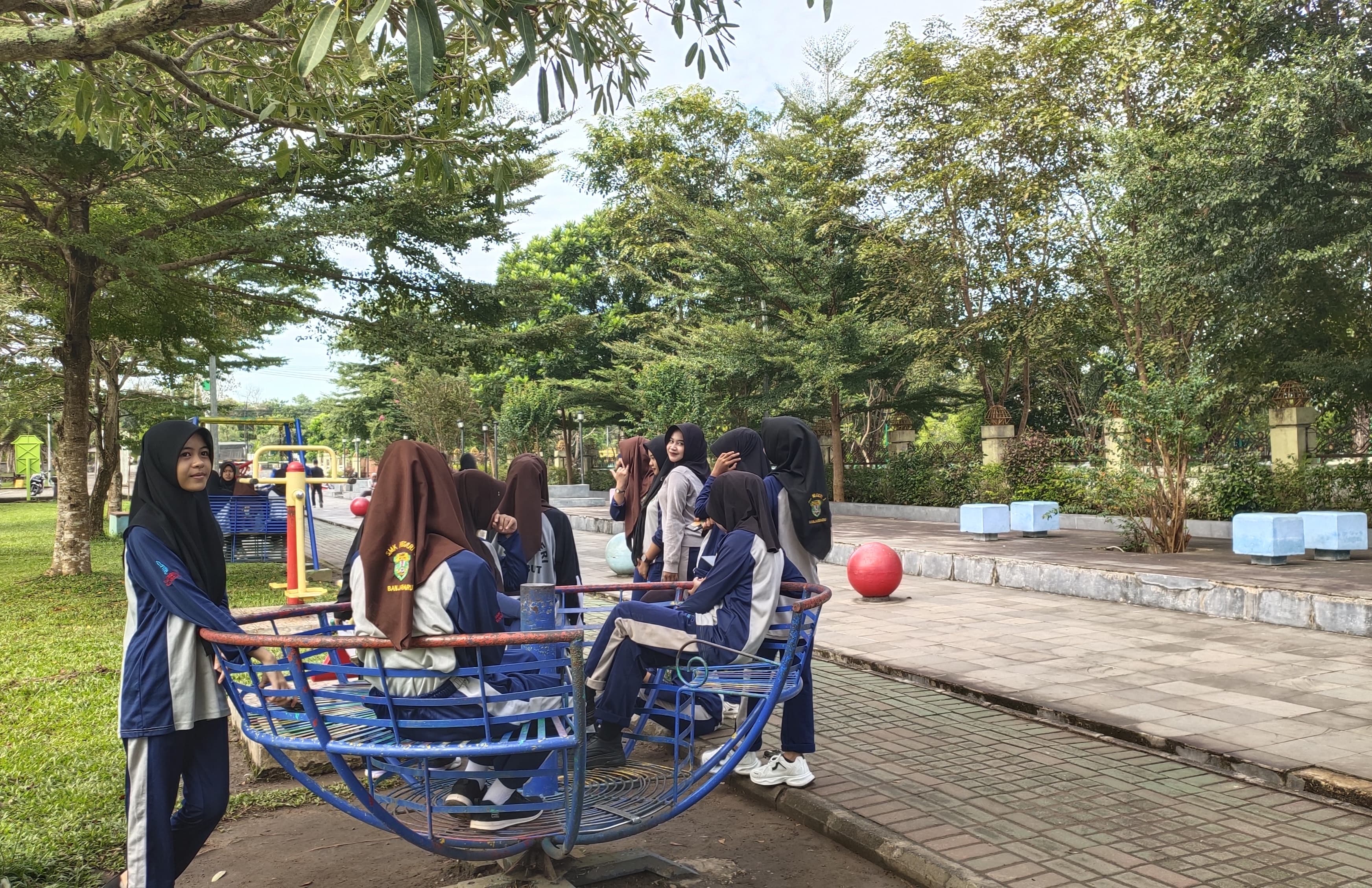 OLAH RAGA: Siswa-siswi SMKN 3 Banjarbaru mengikuti aktivitas fitness outdoor di RTH Al-Munawwarah sambil memanfaatkan fasilitas permainan, Jumat (25/4/2025) pagi. (Foto: Bayu/Radar Banjarmasin)