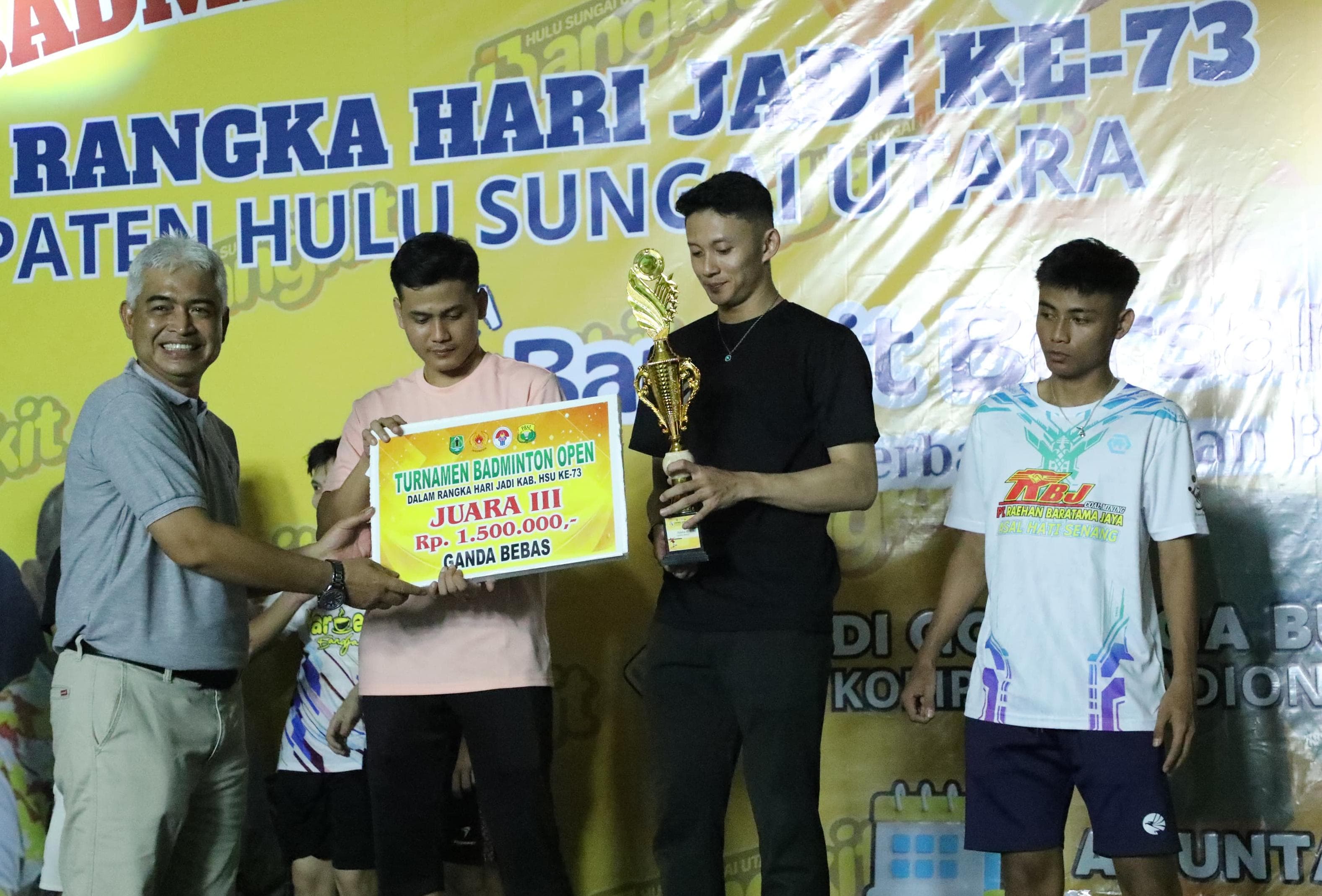 PRESTASI:Wabup HSU, Hero Setiawan menyerahkan trofi juara pada pemenang Badminton Open Meriahkan Harjad HSU Ke-73 di GOR Suryanata, Desa Karias, Minggu (4/5/4045).(Foto:Istimewa)