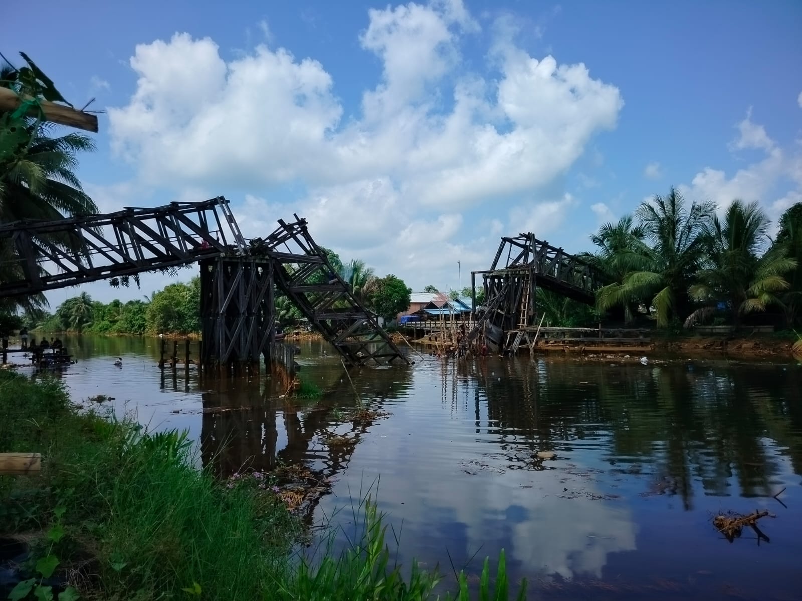 DIBONGKAR:Sejumlah pekerja melepasi kayu Ulin dari badan jembatan yang ambruk di Kecamatan Anjir Pasar.(Foto:Maulana/Radar Banjarmasin)