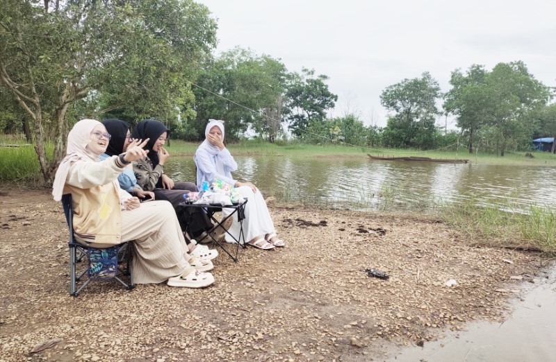 MELEPAS PENAT: Dija dan tiga temannya duduk santai di tepi Danau Galuh Cempaka, Banjarbaru, menikmati suasana tenang dan pemandangan alam yang menyejukkan, Jumat (9/5) sore.