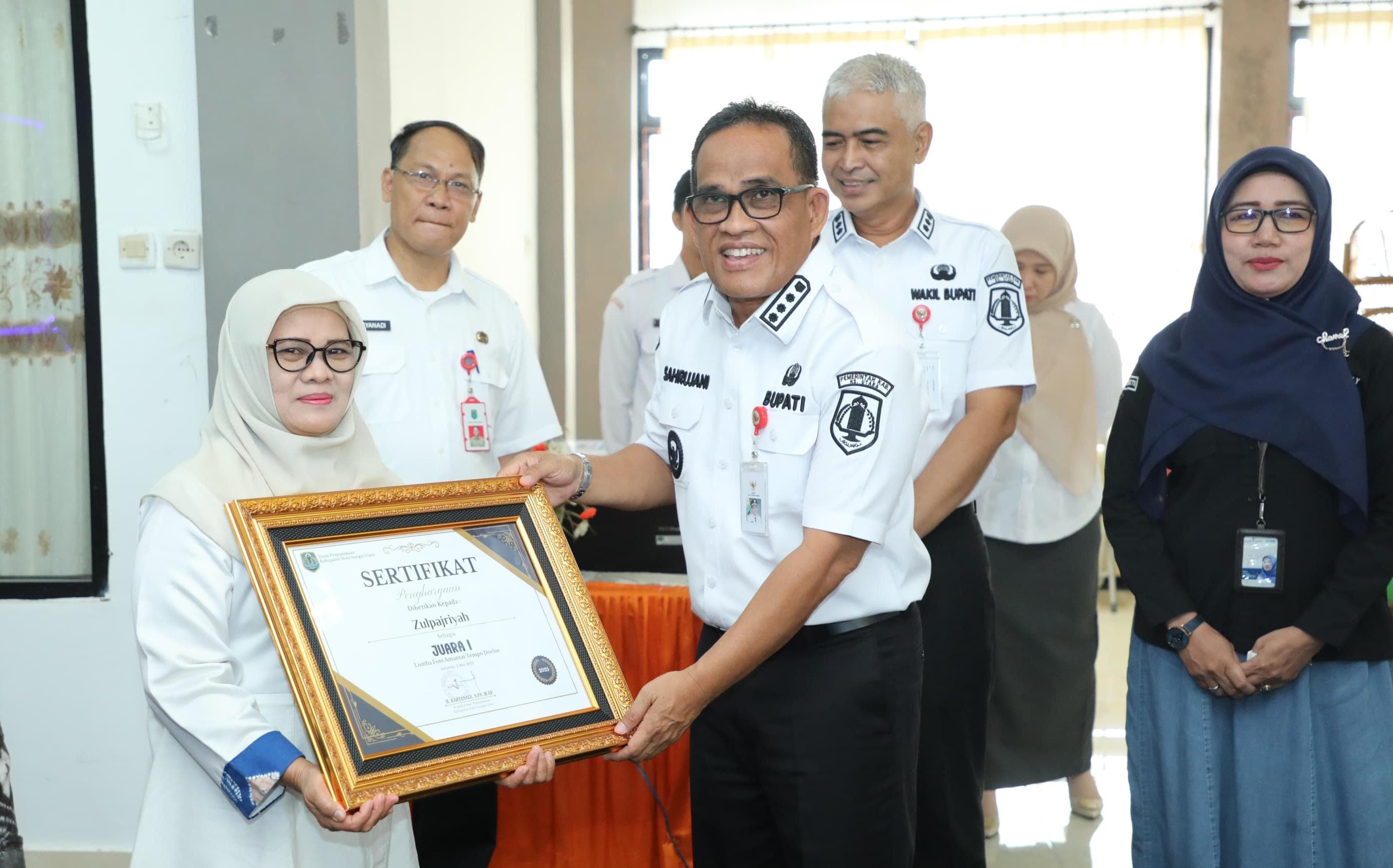 MOMEN:Bupati Kabupaten HSU, H Sahrujani didampingi Wakil Bupati HSU, Hero Setiawan menyerahkan hadiah pemenang foto Amuntai Tempo Doeloe yang digelar Dispersip HSU.(Foto:M Akbar/Radar Banjarmasin)