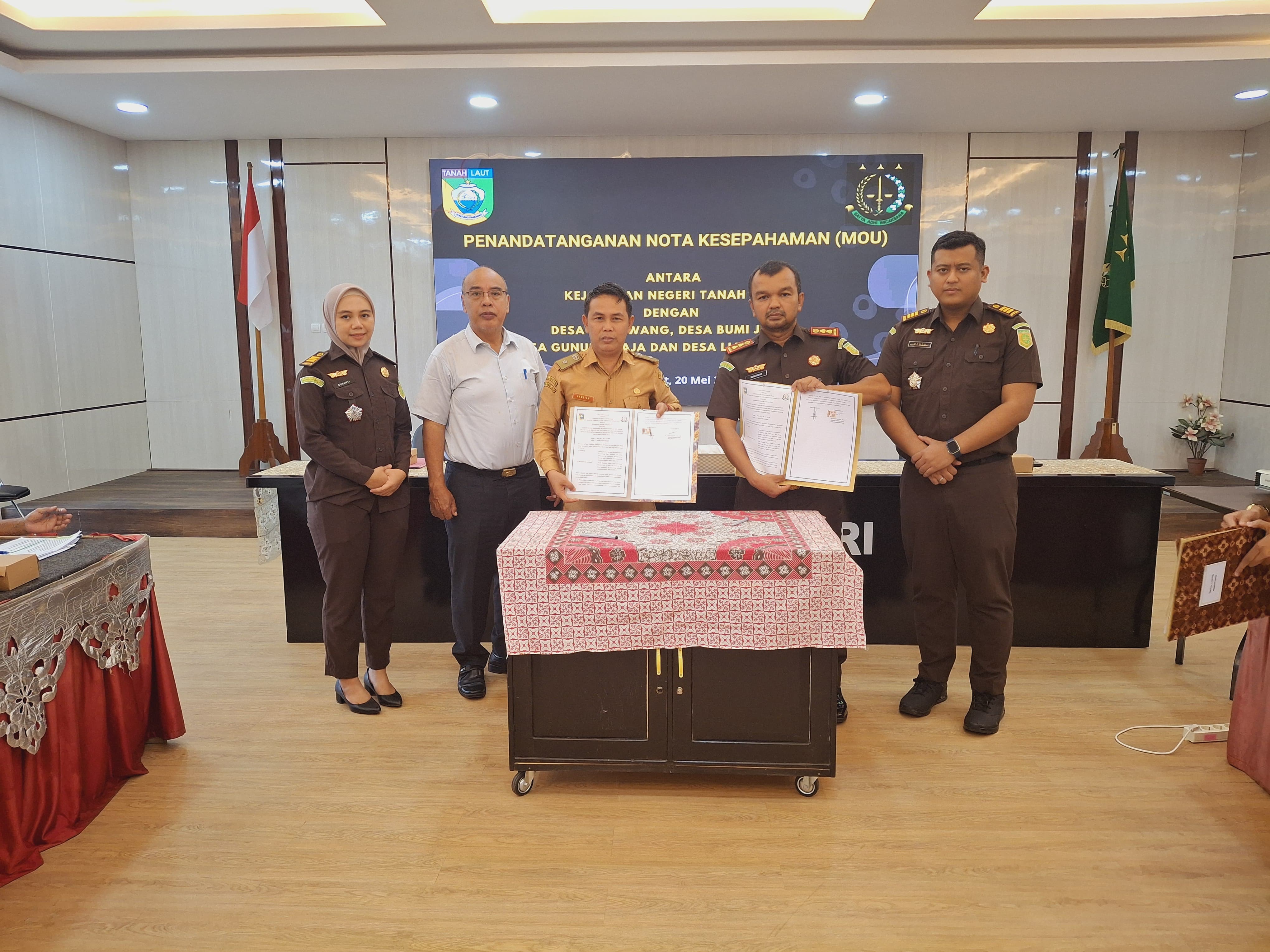 KERJA SAMA: Kepala Kejari Tala Munandar (kanan) menunjukkan dokumen MoU dengan Kepala Desa Gunung Raja Samsiar.