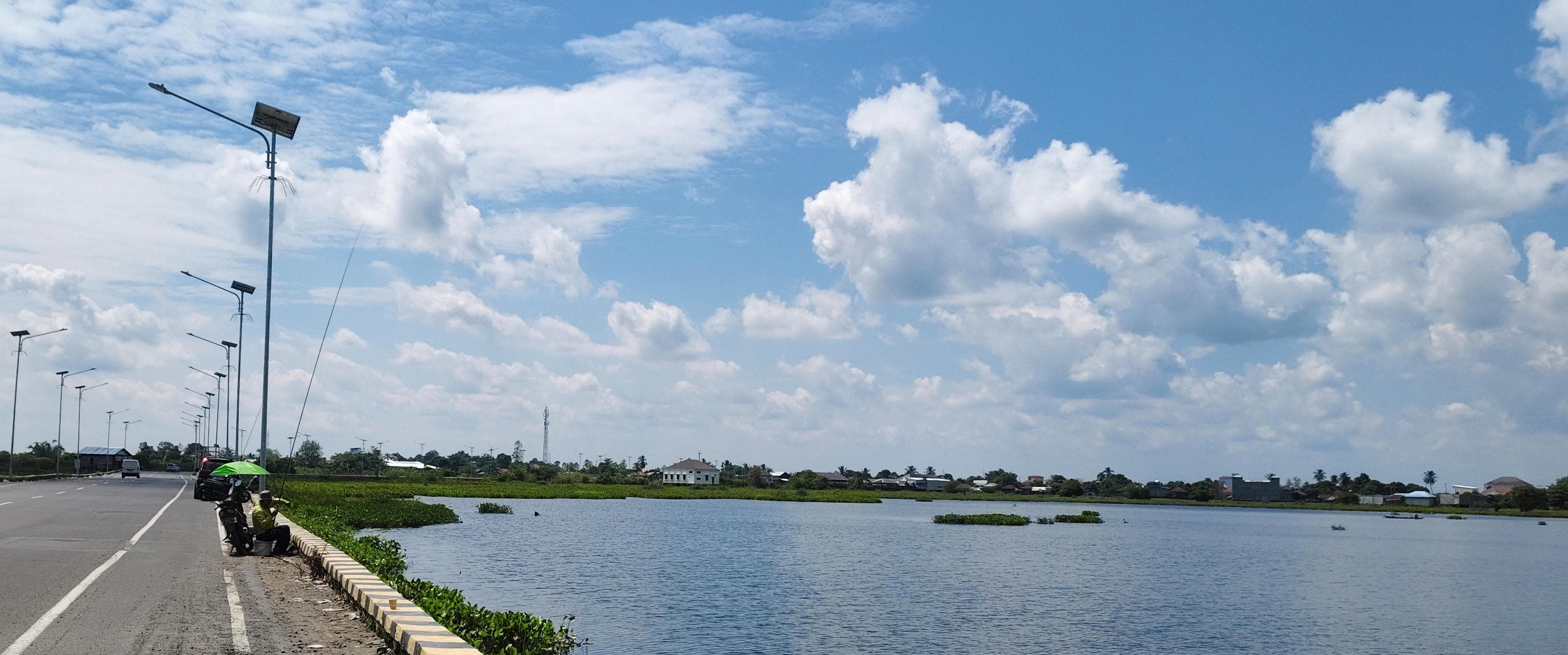 HOBI: Para pemancing memanfaatkan tepi jalan by-pass Haji Fachrudin Amuntai sebagai spot mancing. (Foto: M.Akbar/Radar Banjarmasin)