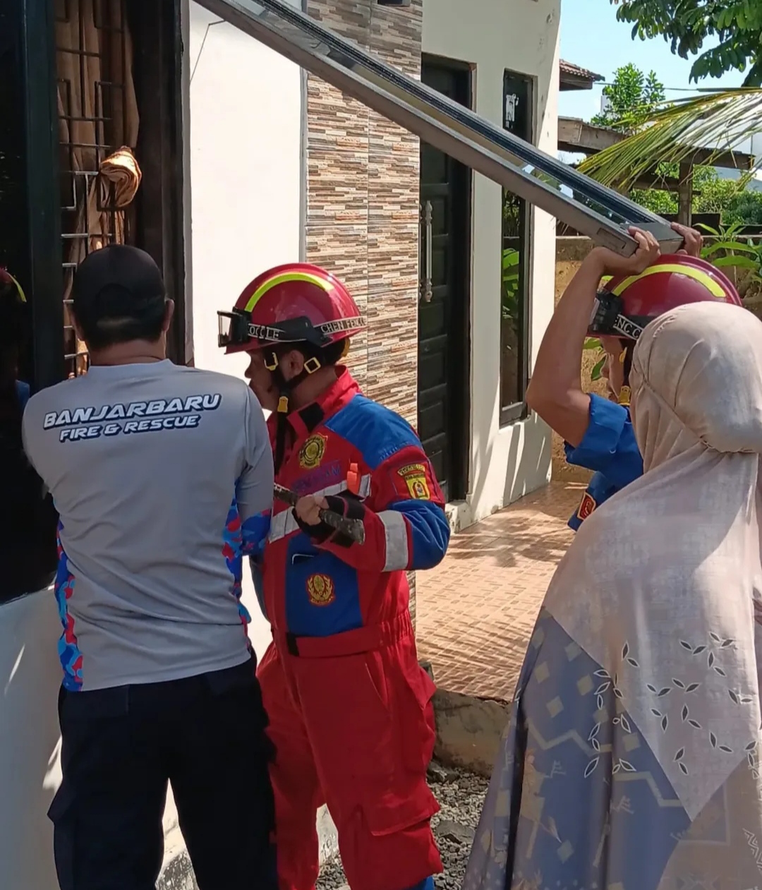 PENYELAMATAN: Aksi petugas UPT Damkar Banjarbaru saat menyelamatkan anak perempuan yang terkunci di dalam rumahnya. (UPT Damkar Banjarbaru untuk Radar Banjarmasin)