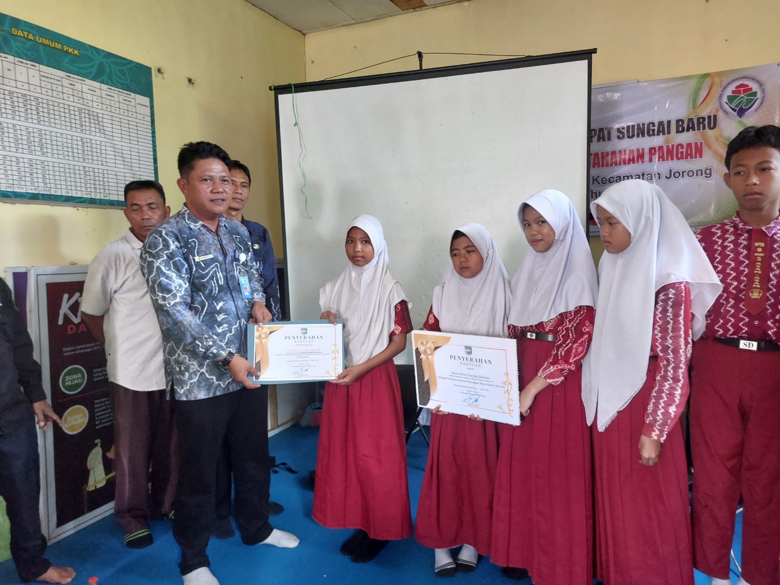 BANTU: Kepala Desa Simpang 4 Sungai Baru Heriyanto saat menyerahkan bantuan beasiswa bagi pelajar kurang mampu hasil dari PAD BUMDes Karya Putra Pribumi (KPP) kepada para penerima.
