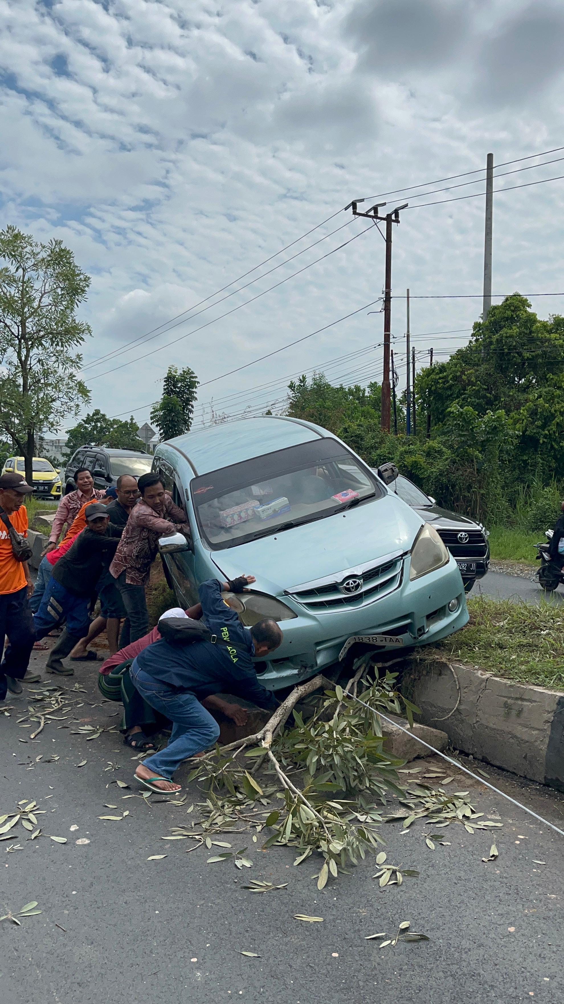 EVAKUASI:Damkar Banjarbaru bersama warga sekitar saat evakuasi mobil yang naik ke trotoar Jalan Trikora, Banjarbaru.(Foto:Damkar Banjarbaru untuk Radar Banjarmasin)