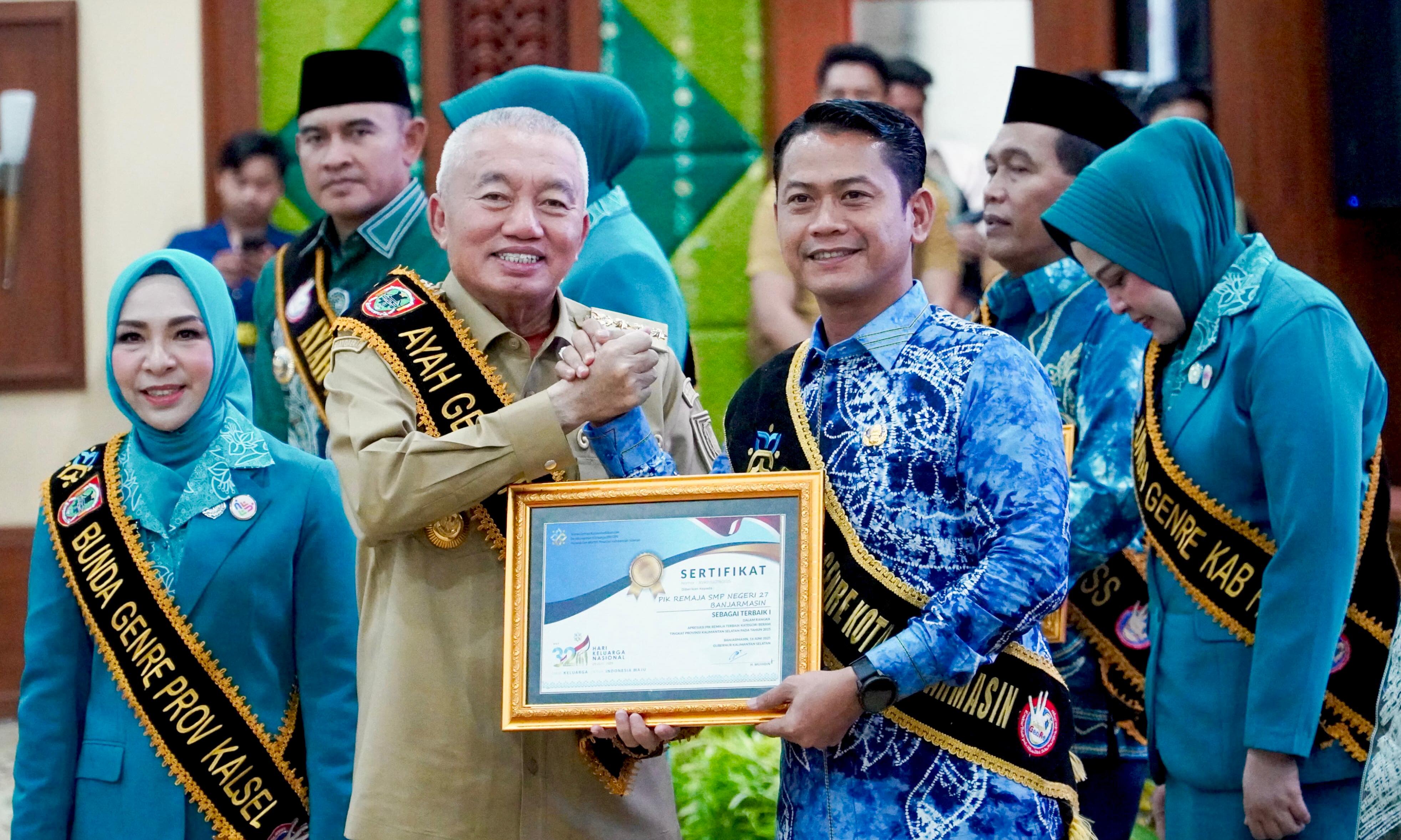 TERBAIK:Gubernur Kalsel H Muhidin menyerahkan penghargaan untuk PIK Remaja SMP Negeri 27 Banjarmasin sebagai Terbaik I, diterima oleh Wali Kota Banjarmasin HM Yamin HR.(Foto:Pemko Banjarmasin)
