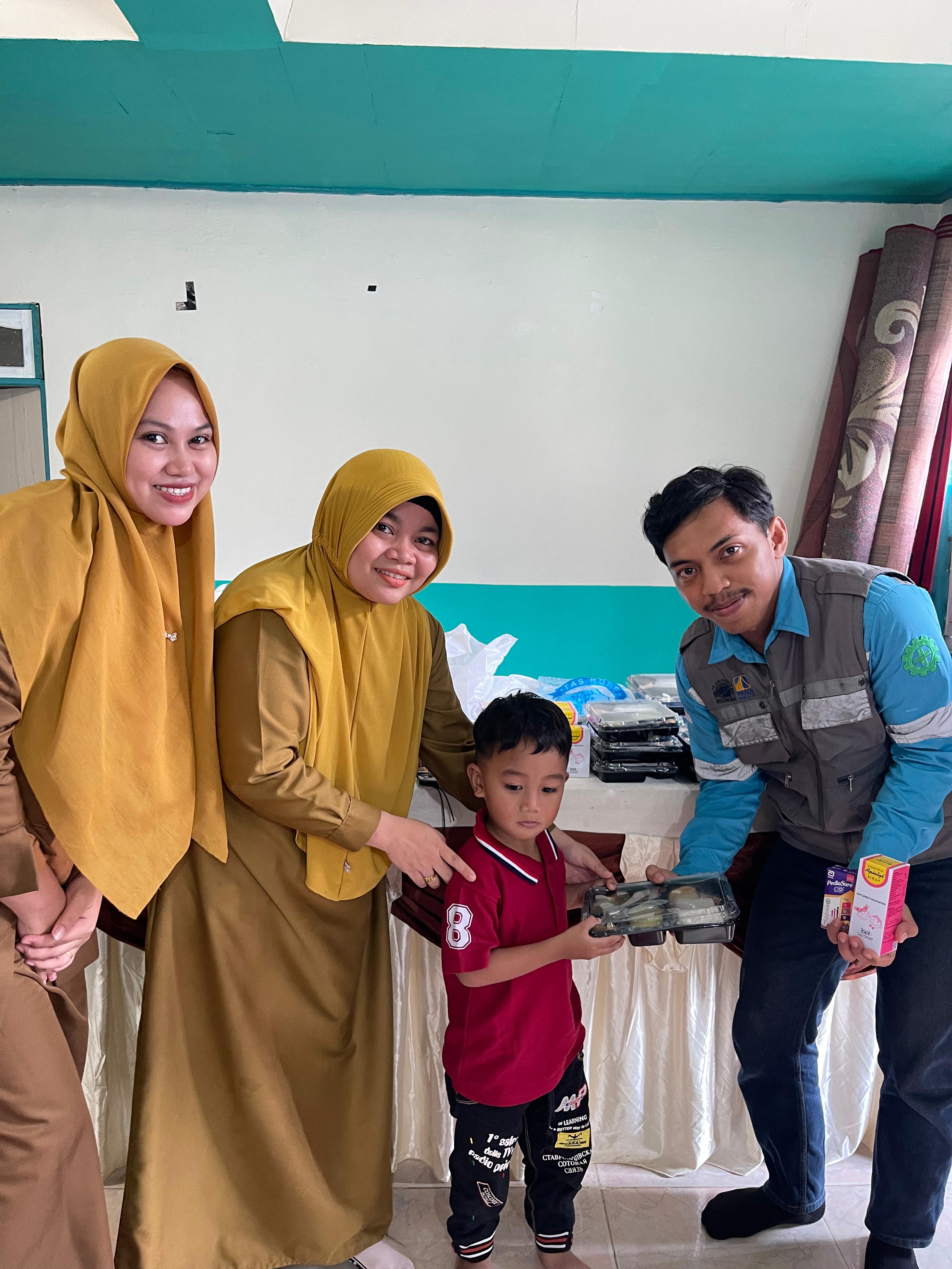 SERAHKAN: Perwakilan PAMA ARIA menyerahkan makanan tambahan kepada balita di Desa Sungai Danau.