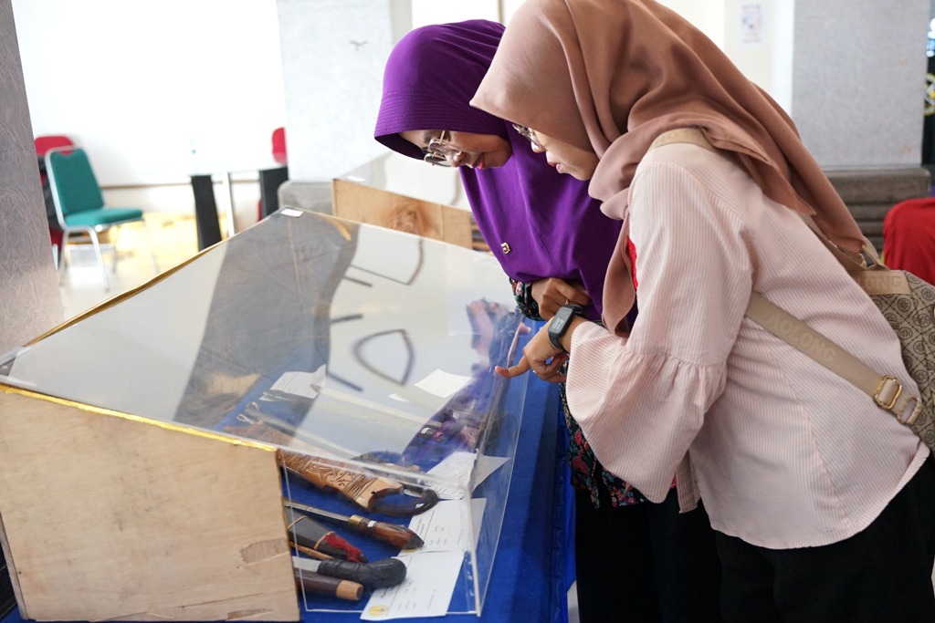AJANG EDUKASI: Dua pengunjung perempuan tampak serius memperhatikan detail ornamen pada bilah keris yang dipamerkan.