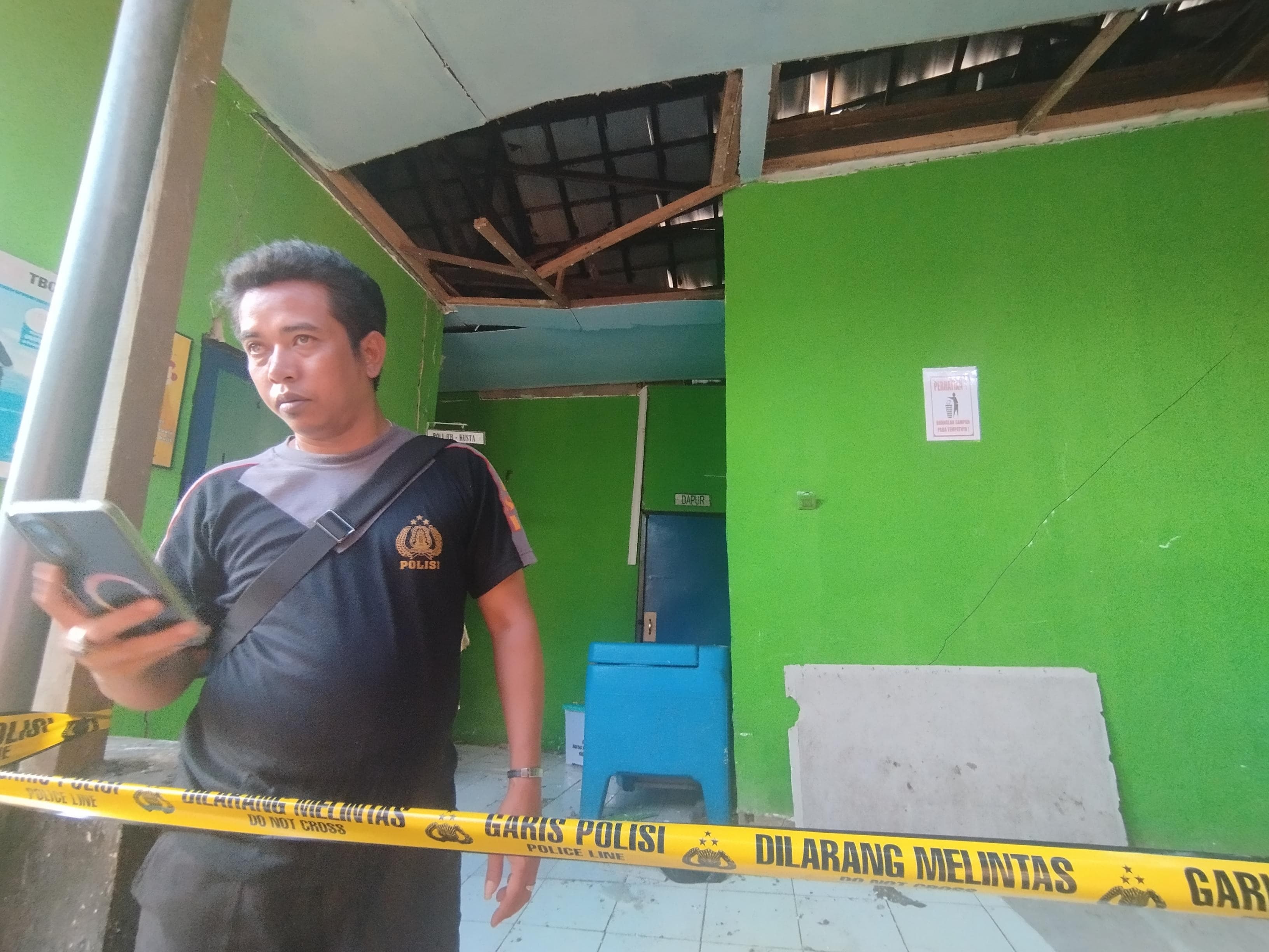 BERJAGA: Sekuriti Puskesmas Aluh-Aluh saat meninjau lokasi ruang rawat inap yang dipasangi garis polisi usai ambruk. (FADLAN ZAKIRI/RADAR BANJARMASIN)