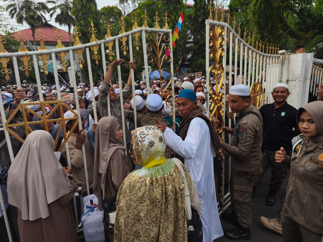 JAGA KETAT: Petugas Satpol PP Banjar berjaga di gerbang Mahligai Sultan Adam, mengatur arus masuk keluarga jemaah haji yang memadati lokasi penyambutan, Kamis (3/7/2025).