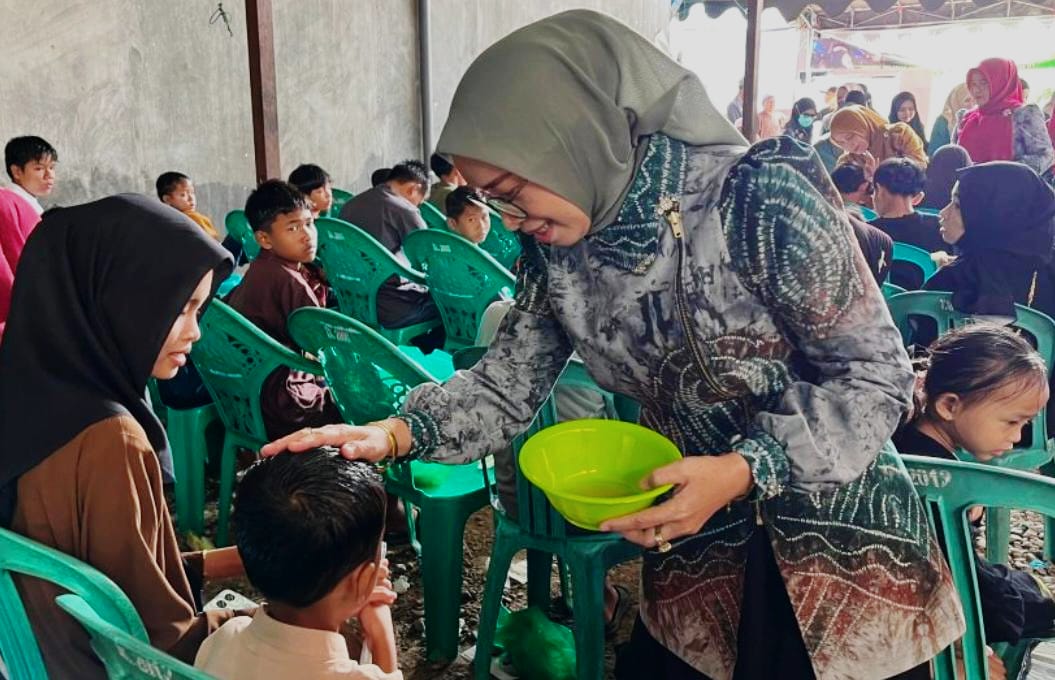 MOMEN:Ketua TP PKK HSU, Hj Murniati Sahrujani mengoleskan anak yatim di Desa Palimbagan Sari, Kecamatan Haur Gading, Kabupaten HSU, Minggu (6/7/2025).